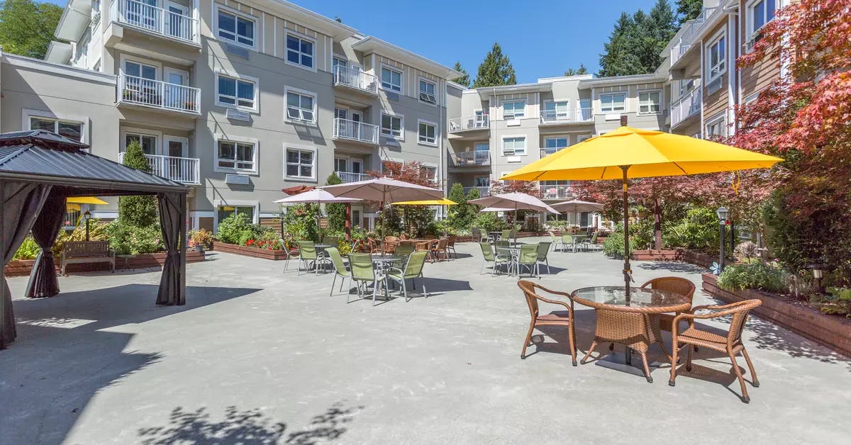 beautiful courtyard with patio furniture and umbrellas at chartwell cedarbrooke retirement residence