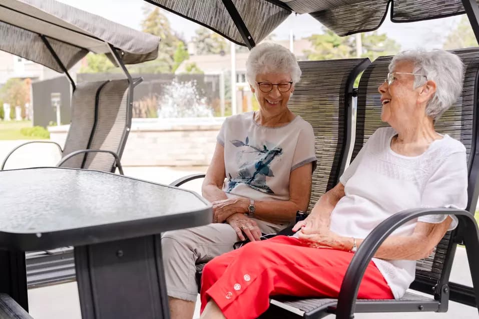 Chartwell senior residents chatting outside in lounge chair