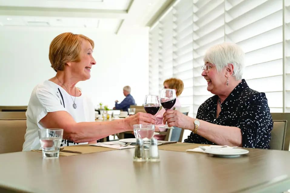 Residents enjoying a glass of wine together in the bright dining room at a Chartwell retirement residence / Résidents partageant un verre de vin dans la salle à manger lumineuse d’une résidence pour retraités Chartwell