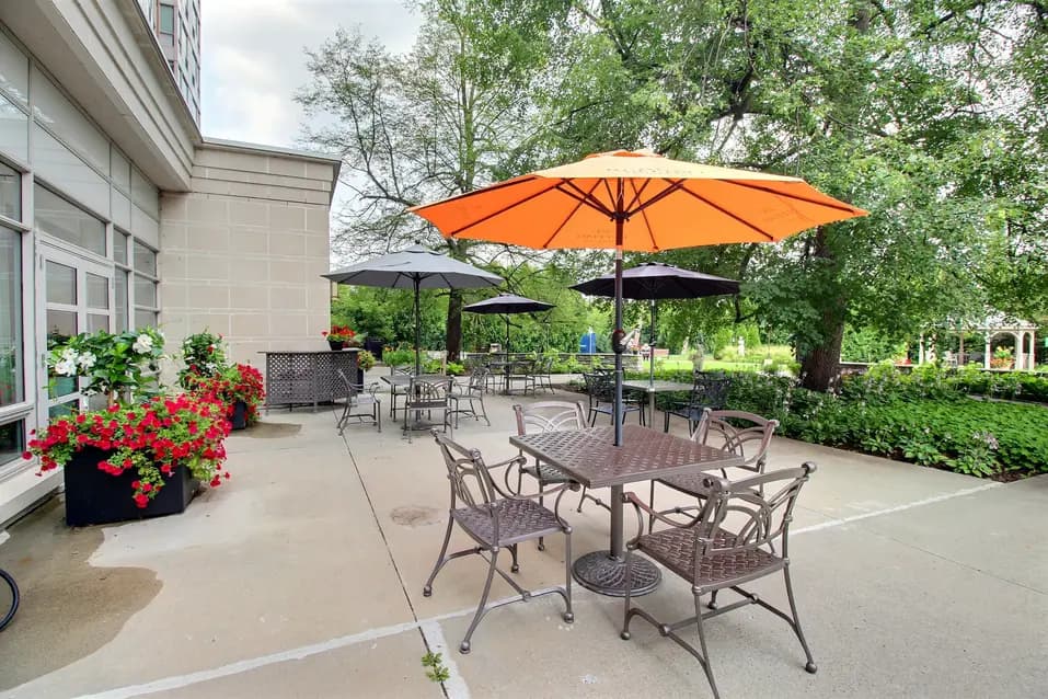 Exterior patio with parasol tables and chairs at Chartwell Rockcliffe / Patio extérieur avec tables et chaises équipées de parasols à Chartwell Rockcliffe