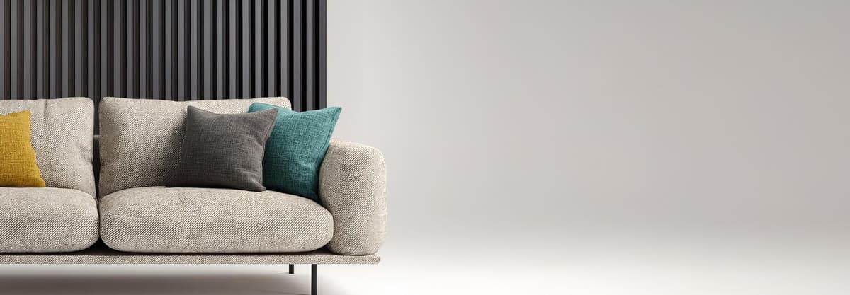 Sofa with three coloured cushion in front of the dark grey wood panel wall / Canapé avec trois coussins colorés devant un panneau mural en bois gris foncé