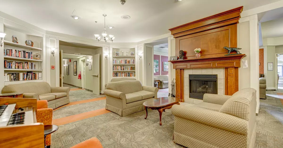 Lounge with a piano, bookshelves and a fireplace at Chartwell Le Wellesley / 
Salon avec piano, étagères et foyer chez Chartwell Le Wellesley