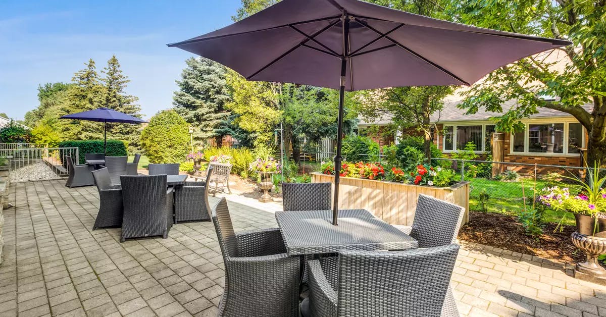 Outdoor patio with comfortable furniture and gorgeous gardens at Chartwell Orchards Retirement Residence