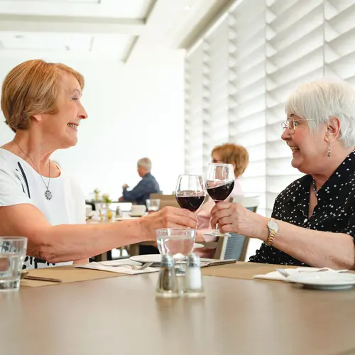 Senior women at Chartwell retirement residence are cheering at the dining table / Les femmes âgées de la maison de retraite Chartwell se réjouissent à la table à manger