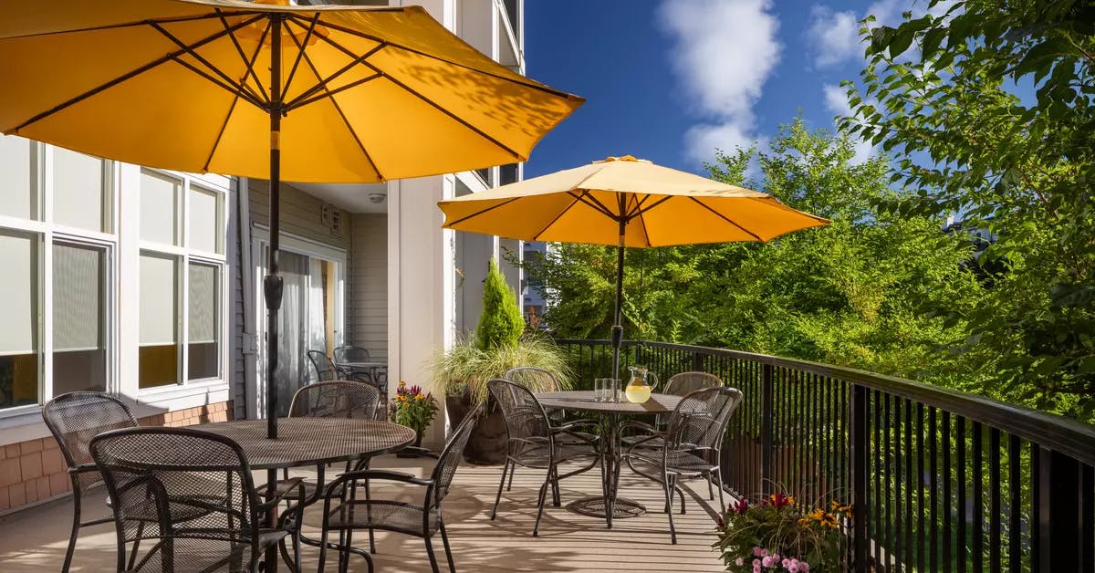 beautiful patio with furniture and umbrellas at chartwell hampton house retirement residence